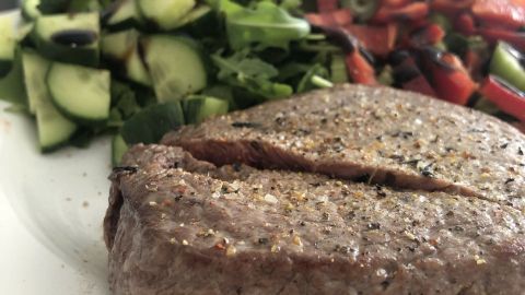 Ein saftiges Steak liegt auf einem Teller, umgeben von frischem Gemüse und einer bunten Salatmischung.