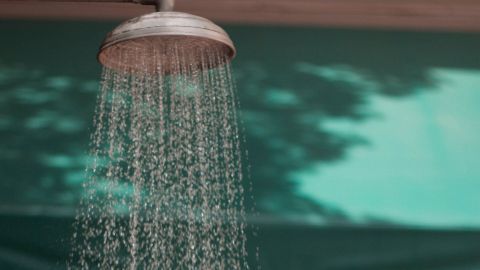 Eine Frau steht unter einer Dusche, während kaltes Wasser auf sie herabströmt, um Muskelkater zu lindern.