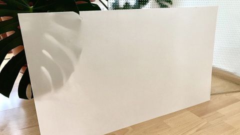 Ein Lichtdiffusor steht auf dem Boden, beleuchtet von Tageslicht, umgeben von grünen Pflanzen im Hintergrund.