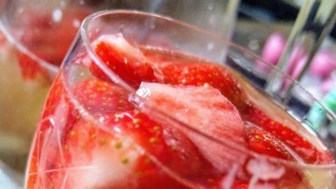Ein elegantes Glas Maibowle mit frischen Erdbeeren, gefüllt und kühl in einer geselligen Umgebung.
