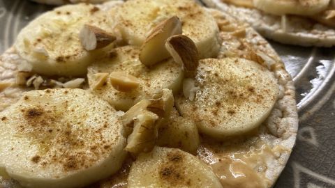 Gesunde Reiswaffeln mit Bananen und Nüssen liegen appetitlich auf einem dekorativen Teller, bereit zum Snacks während des Netflixens.