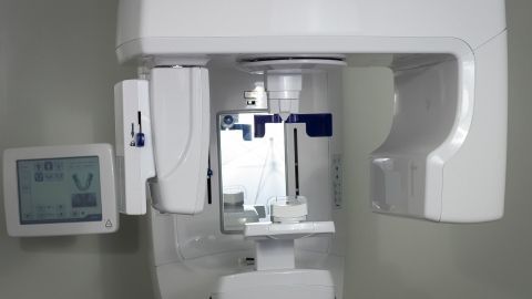 Ein Röntgengerät steht bereit, um Zahnuntersuchungen durchzuführen, während der Raum klinisch und sauber wirkt.