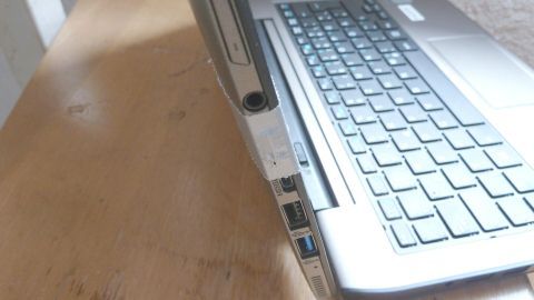 Ein Laptop steht schräg auf einem Tisch, während der Kartenslot für die microSD-Karte sichtbar ist, was auf einen Defekt hindeutet.