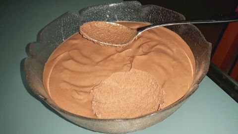 Eine cremige Mousse au Chocolat steht in einer Schüssel, während ein Löffel die geschmeidige Schokoladenmasse anhebt.