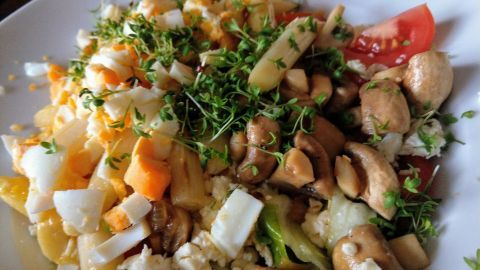 Ein bunter Salat mit karamellisiertem Spargel, Nüssen und frischen Kräutern auf einem weißen Teller, appetitlich angerichtet.