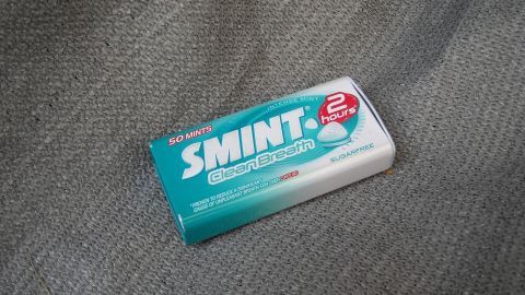 Ein Taschenaschenbecher liegt auf einem grauen Untergrund. Er dient als praktisches Behältnis für Zigarettenreste.