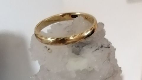 Mit diesem Tipp kann es gut gelingen, einen verlorenen Ring aus einem Badewannenabfluss herauszubekommen. Ein goldener Ehering steckt in einer festen, weißen Substanz auf einem langen Stab, gehalten in einem Wohnraum.