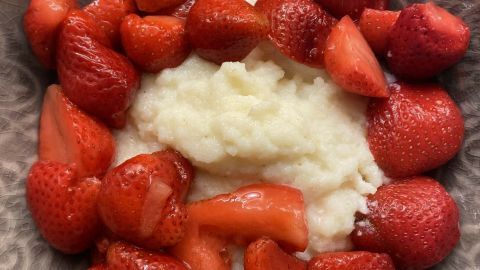 In einer Schüssel liegt kalter Grießbrei, umgeben von frischen, roten Erdbeeren, die appetitlich angerichtet sind.