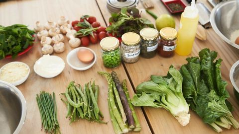 Frische Gemüse und Zutaten liegen auf dem Tisch, bereit für die Zubereitung einer vegetarischen Mahlzeit in einer Küche.
