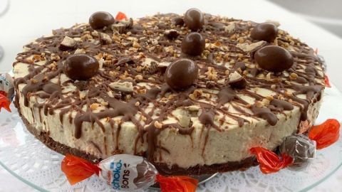 Eine köstliche Schokobon-Torte ohne Backen liegt auf einem filigranen Teller, dekoriert mit Schokolade und Bonbons.