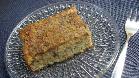 Ein Stück Butter-Mandel-Kuchen auf einem dekorativen Teller, bereit zum Servieren, umgeben von einem blauen Hintergrund.