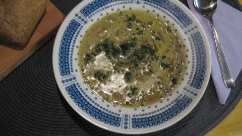 Eine Schüssel mit feiner Linsensuppe steht auf einem Tisch, umgeben von Bread und einem Löffel, auf einem stilvollen Platz.