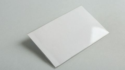 Ein leeres Blatt Papier liegt flach auf einem grauen Untergrund, bereit für eine einfache To-do-Liste.
