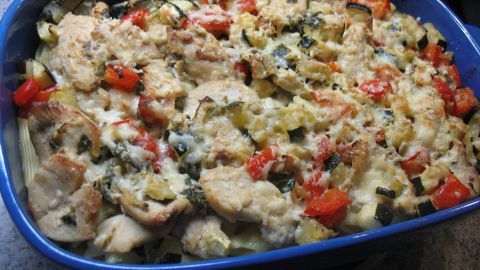 Ein herzhaftes Gemüse-Hähnchen-Gratin liegt in einer blauen Auflaufform und zeigt eine Mischung aus Hühnchen und Gemüse.