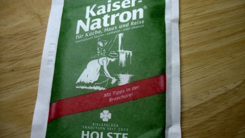 Eine Packung Kaiser-Natron liegt auf einem Holztisch, bereit zum Einsatz gegen Johannisbeer-Konfitüre-Flecken.