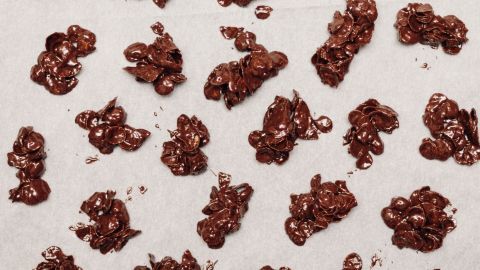 Auf einem hellen Untergrund liegen schokoladige Knuspersnacks, die in unregelmäßigen Formen verteilt sind.