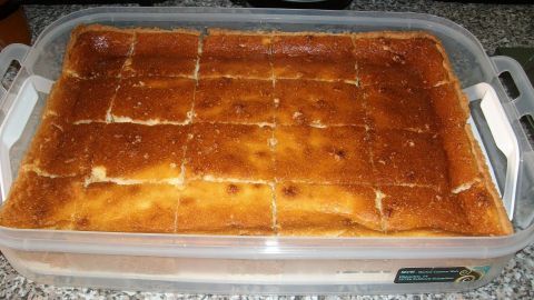 Ein Käsekuchen ist auf einer Arbeitsfläche platziert, in rechteckige Stücke geschnitten, bereit zum Servieren.