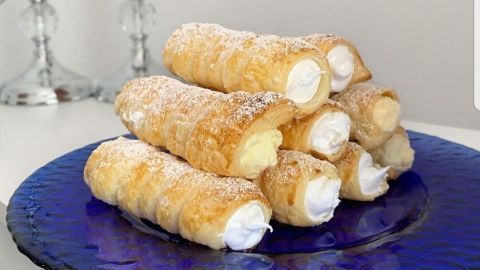 Schaumrollen auf einem blauen Teller, gefüllt mit italienischem Eischnee, liegen appetitlich übereinander gestapelt.