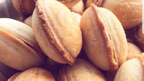 Goldbraune, halbkugelige Oreschki liegen in einem Behälter, bereit zum Genießen, umgeben von sanfter Beleuchtung.