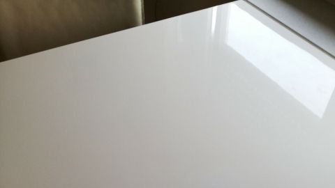 Ein heller Hochglanztisch reflektiert Licht, während er auf einer glatten Oberfläche steht, die sauber und modern wirkt.