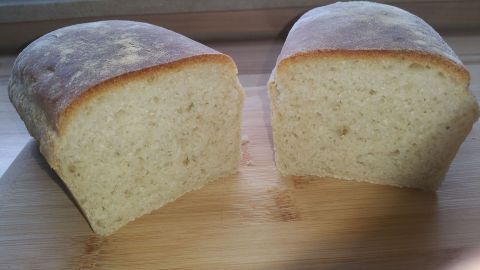 Ein frisch gebackenes Toastbrot mit weicher Kruste liegt auf einem Holzbrett, aufgeschnitten und bereit zum Servieren.