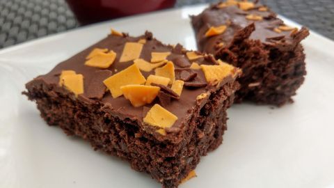 Saftige Kokos-Kuchenstücke mit Schokolade und Karamellstückchen auf einem weißen Teller, umgeben von einem modernen Hintergrund.