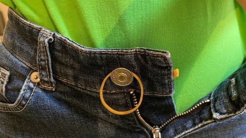 Ein defekter Reißverschluss wird durch einen Schlüsselring provisorisch fixiert, während er an einer Jeans getragen wird.