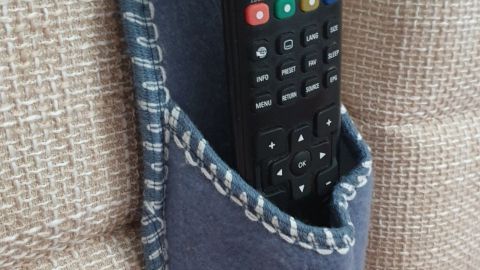 Eine Fernbedienung ist in einer blauen Tasche am Bettrücken verstaut, sodass sie jederzeit griffbereit ist.