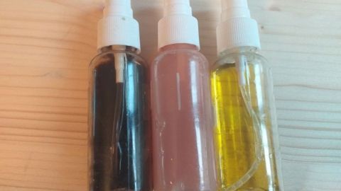 Drei Flaschen mit Spülmittel in verschiedenen Farben stehen auf einem Holzuntergrund, bereit zum Einsatz in der Küche.