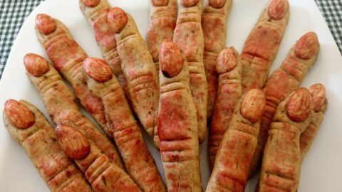 Knusprige Hexenfinger in Form von Keksen liegen auf einem weißen Teller - perfekt für Halloween-Dekoration und Snacks.
