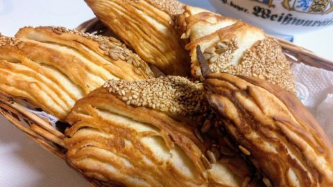 Flaky Laugendreiecke sind in einem Korb angeordnet, umgeben von einer hellen Tischoberfläche und einem bayerischen Geschirr.