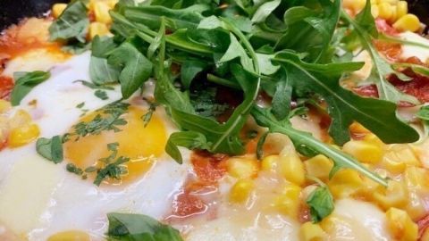 Saftige Eier schwimmen in einer würzigen Tomatensauce mit Mais, überbacken mit Mozzarella und frischen Kräutern.