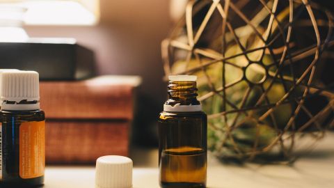 Ölfläschchen stehen auf einem Tisch, bereit zur Anwendung für Haut und Haare, umgeben von sanfter Beleuchtung und Dekoration.