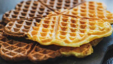 Fluffige Marmorwaffeln liegen übereinander auf einem schwarzen Teller und laden zum Genießen ein.