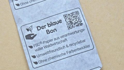 Der blaue Kassenbon hat keine chemischen Stoffe, die die Umwelt schädigen. Der blaue Kassenzettel liegt auf einem hellen Hintergrund und zeigt umweltfreundliche Informationen sowie einen QR-Code.