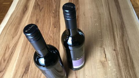 Zwei Weinflaschen mit Drehverschlüssen stehen auf einem Holztisch. Sie sind bereit zum Öffnen und Servieren.