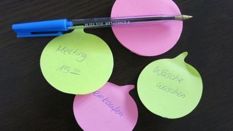 Bunte Haftnotizen liegen auf einem Tisch, während ein Stift darauf platziert ist, um Gedanken und Ideen festzuhalten.