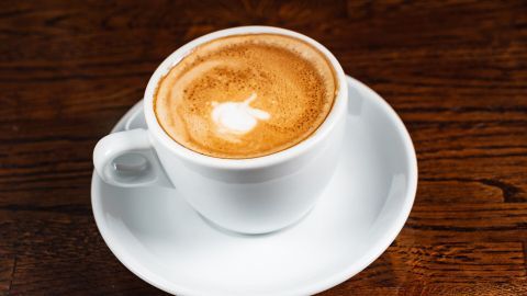 Eine Tasse Cappuccino mit schönem Milchschaum steht auf einem Holzuntergrund, bereit zum Genießen mit der Senseo-Maschine.