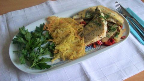 Zanderfilet liegt auf buntem Paprika-Fenchel-Gemüse, umgeben von knusprigen Kartoffeln und frischer Petersilie.