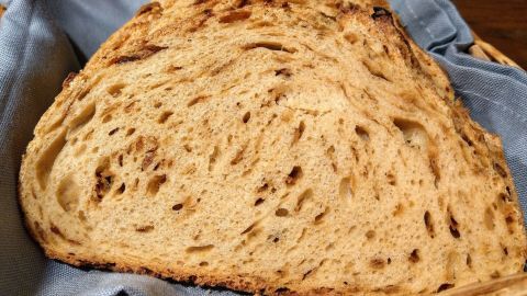 Eine goldbraune Zwiebelkrüstchen-Scheibe liegt auf einem blauen Tuch in einem Korb und wartet auf den Verzehr.