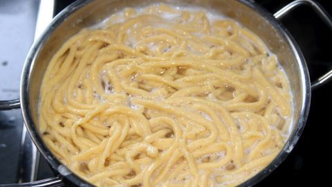 In einem Topf kochen handgemachte Spätzle in sprudelndem Wasser, umgeben von einer modernen Küche.