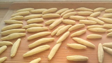 Schwäbische Schupfnudeln liegen in länglichen Formen auf einem Holzbrett, bereit zum Kochen.