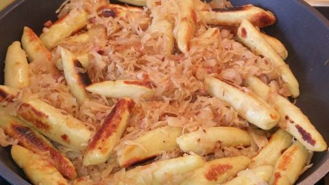 In einer Pfanne sind goldbraun gebratene Schwäbische Krautschupfnudeln mit Sauerkraut angerichtet.