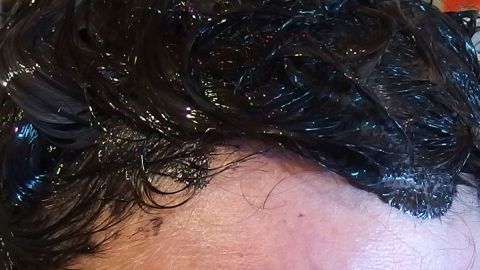 Feuchtes, gefärbtes Haar wird mit Creme behandelt, um Ränder nach dem Haare färben zu vermeiden. Der Hintergrund ist unscharf.