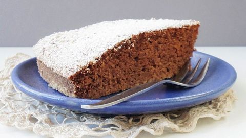 Ein Stück Brownie-Kuchen mit Kidneybohnen liegt auf einem blauen Teller, umgeben von einer dekorativen Serviette.