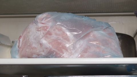 Gefrorenes am Vortag im Kühlschrank auftauen lassen - spart Energie beim Kochen. Eine gefrorene Fleischsorte befindet sich in einem durchsichtigen Beutel, eingelagert im Kühlschrank, um langsam aufzutauen.