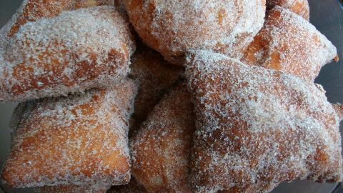 Zuckerbestäubte Schwäbische Fasnetsküchle liegen übereinandergestapelt in einer Glasschüssel und wirken köstlich.
