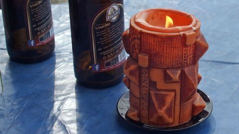 Eine brennende Kerze auf dem Tisch sorgt dafür, dass keine Wespen mehr kommen. Eine dekorative Kerze brennt auf einem Tisch, umgeben von Flaschen, um Wespen fernzuhalten.