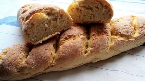 Ein frisches Baguette aus Hartweizengrieß liegt auf einem Küchentuch, mit einer Scheibe herausgeschnitten.