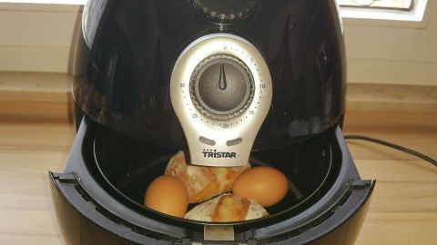 In der Heißluftfritteuse werden Brötchen und Frühstückseier zubereitet, während sie in einer modernen Küche stehen.